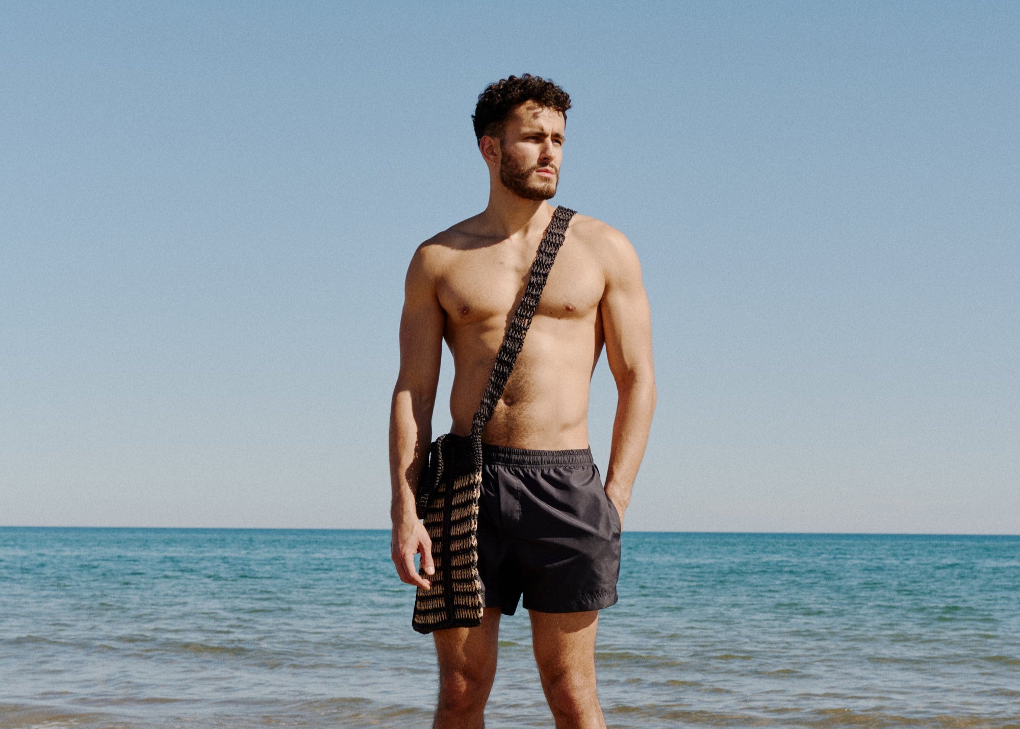 Vince on the beach in Carbon Short Bas Bains with bag