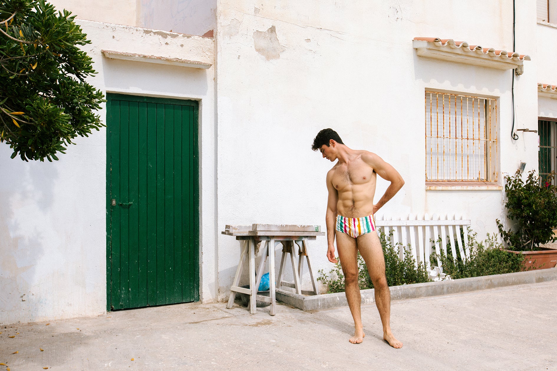 Dani Garcia wearing Paradis Sunga in Eivissa print by Bas Bains in front of Mediterranean white house