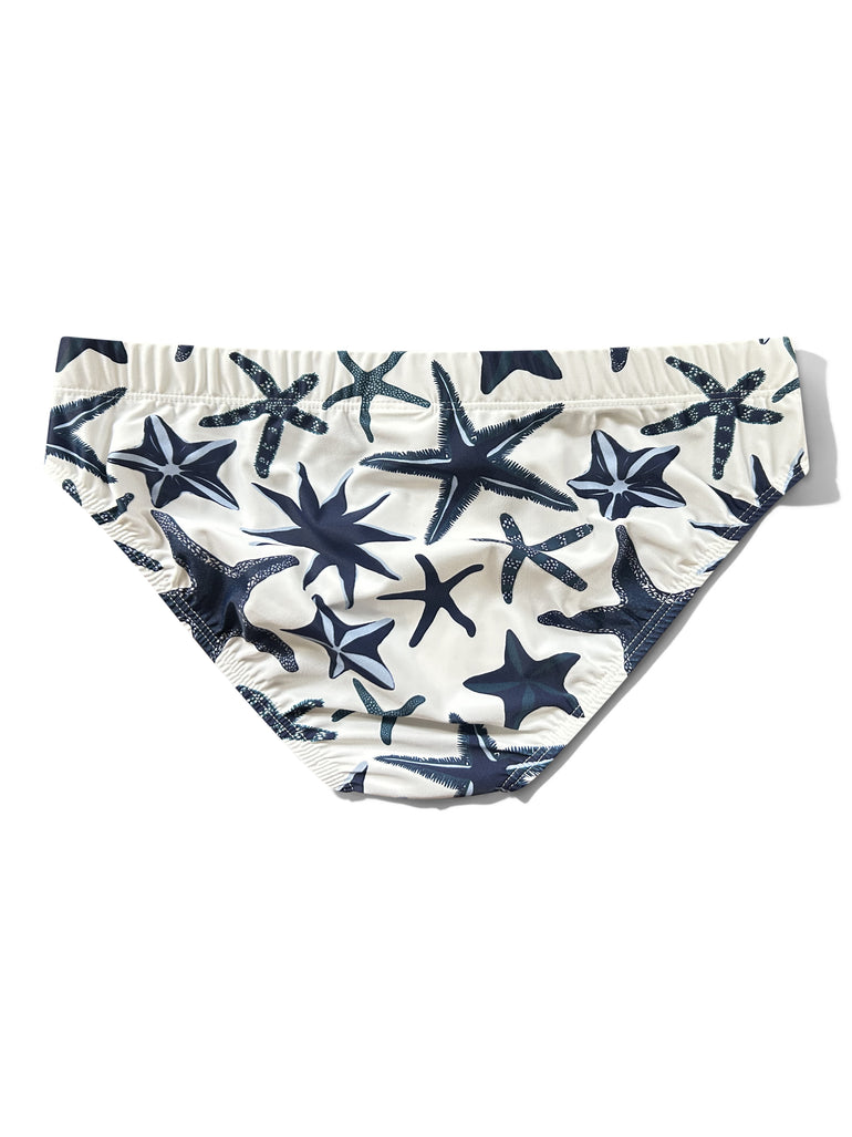 White men's swim slip featuring a navy blue starfish and star pattern, laid flat on a white background.