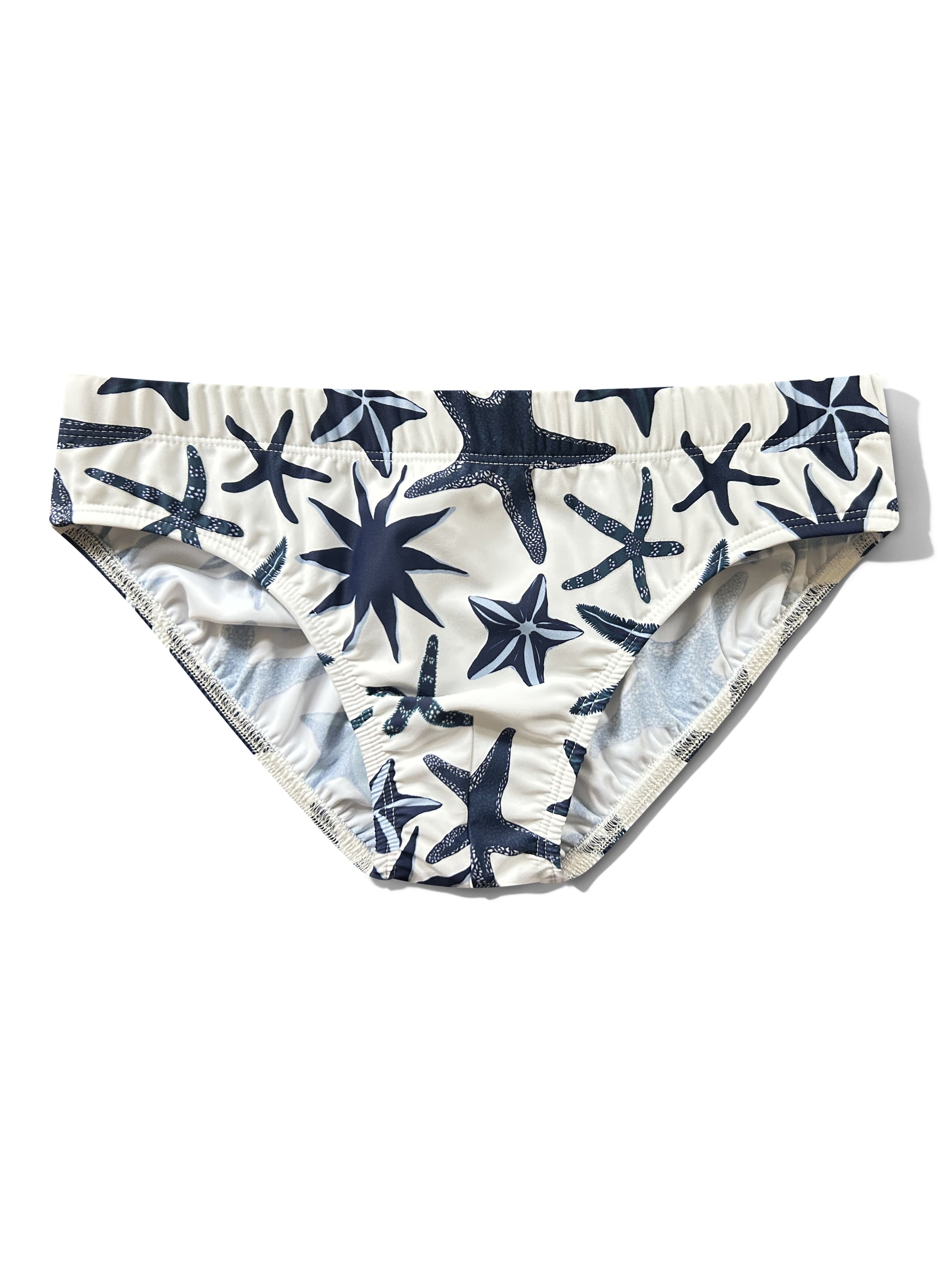 White men's swim slip featuring a navy blue starfish pattern, displayed flat against a white background.