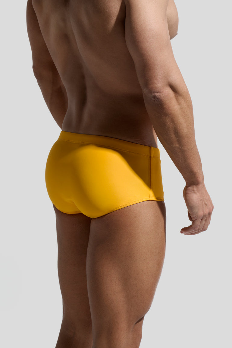 image of swimwear sunga in Mandarin yellow back view on male model by Bas Bains