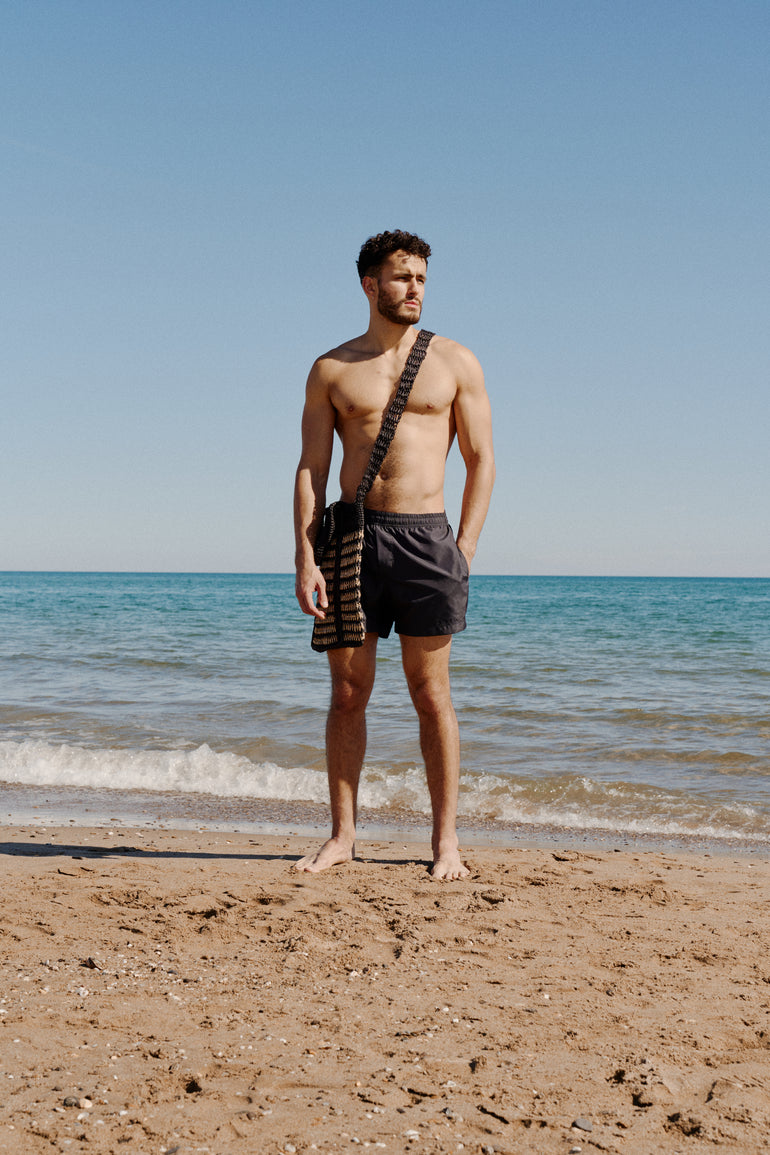 Vince on the beach in Carbon Short Bas Bains with bag